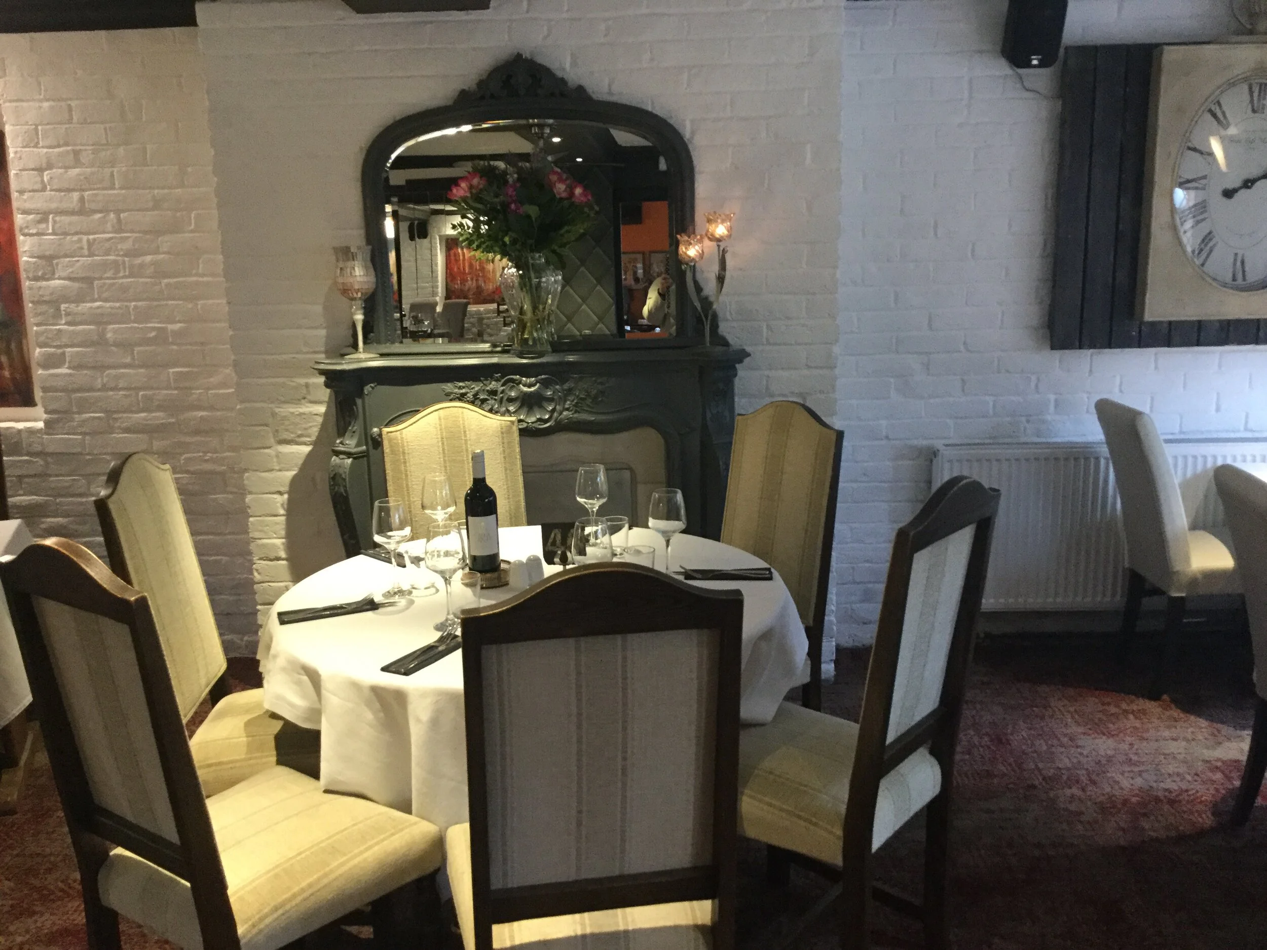 The restaurant at The Woodmancote, white brick walls and an ornate fireplace
